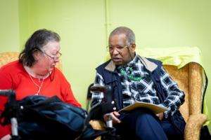Two older people, a man and a woman, sitting side by side, in conversation
