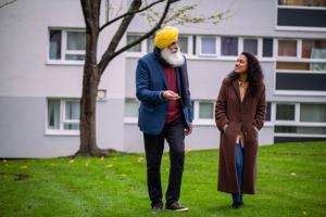 Ac an and a woman, walking outside, on a green grassy bank
