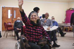 Person sitting in a wheelchair waving at the camera